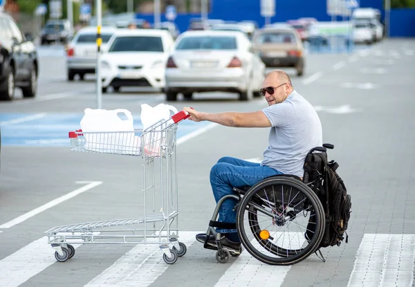 Persona con una discapacidad física empujando carro delante de sí mismo en el estacionamiento del supermercado —  Fotos de Stock