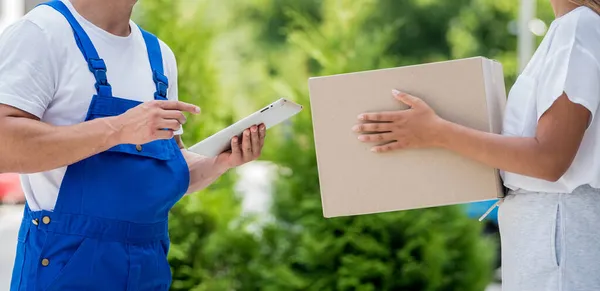 Giovane corriere che consegna merci a una giovane donna a casa — Foto Stock