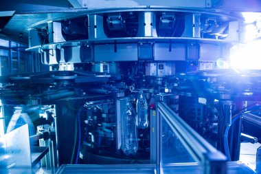 Modern içecek fabrikasında otomatik doldurma makinesi plastik PET şişelerine su doldurur.