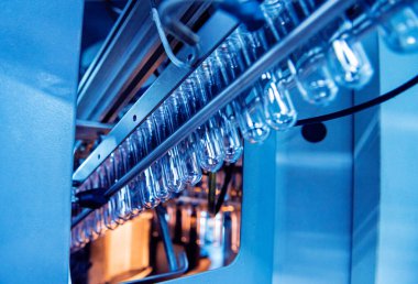 Modern içecek fabrikasında otomatik doldurma makinesi plastik PET şişelerine su doldurur.