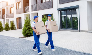 İki nakliye şirketi çalışanı bir minibüse kutu yüklüyorlar..