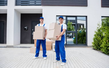 İki nakliye şirketi çalışanı bir minibüse kutu yüklüyorlar..