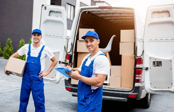 Dos trabajadores de la empresa de mudanzas descargan cajas de minibús en el hogar de los clientes — Foto de Stock