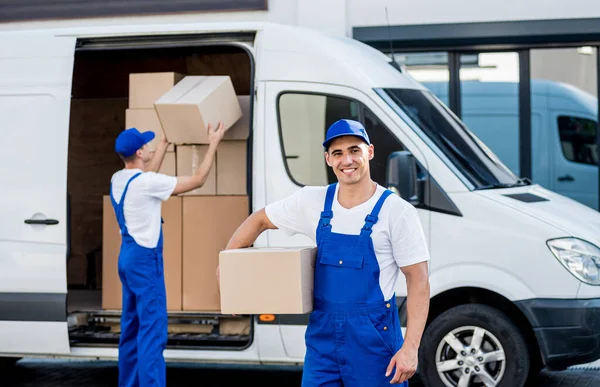 Dos trabajadores de la empresa de mudanzas descargan cajas de minibús en un nuevo hogar —  Fotos de Stock