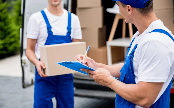 Dos trabajadores de la empresa de mudanzas descargan cajas de minibús en un nuevo hogar — Foto de Stock