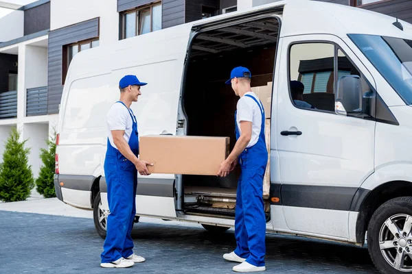 Два працівники компаній, що вивозять, завантажують коробки в мікроавтобус . — стокове фото