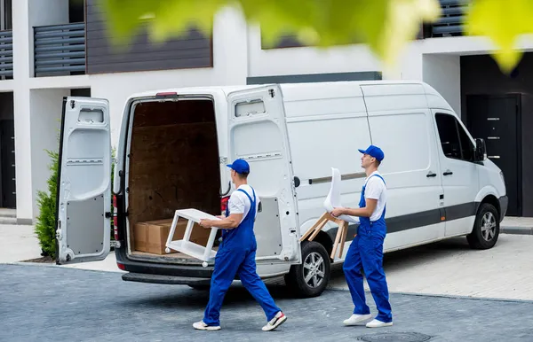 Два працівники компаній, що вивозять, завантажують коробки та меблі в мікроавтобус . — стокове фото