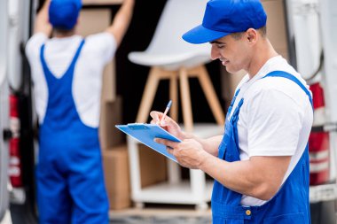 İki nakliye şirketi çalışanı minibüsten yeni eve kutular boşaltıyor.