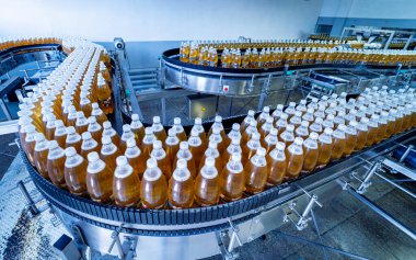 Modern bir içecek fabrikasında meyve suyu veya su için şişeli taşıyıcı bant