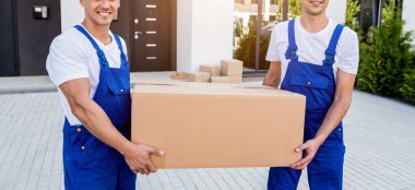 İki nakliye şirketi çalışanı minibüsten yeni eve kutular boşaltıyor.