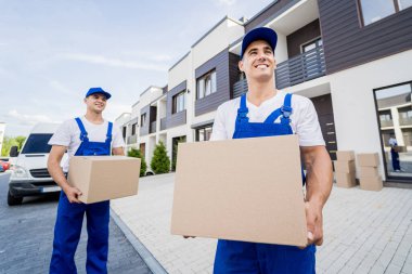 İki nakliye şirketi çalışanı minibüsten müşterilerin evlerine kutu indiriyor.