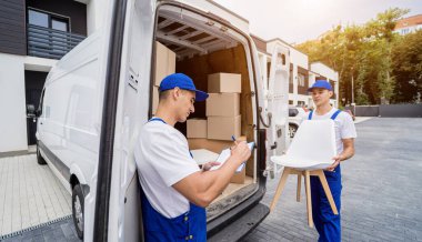 İki nakliye şirketi çalışanı bir minibüse kutu ve mobilya yüklüyorlar..