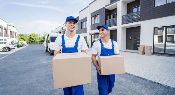 Dos trabajadores de la empresa de mudanzas descargan cajas de minibús en el hogar de los clientes —  Fotos de Stock