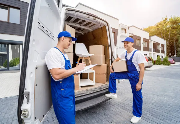 Dos trabajadores de la empresa de mudanzas que descargan cajas y muebles del minibús —  Fotos de Stock