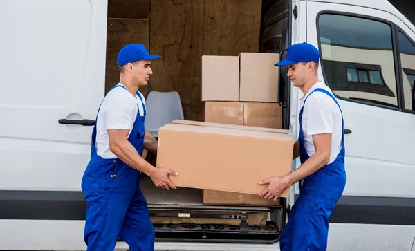 Dos trabajadores de la empresa de mudanzas descargan cajas de minibús en un nuevo hogar —  Fotos de Stock