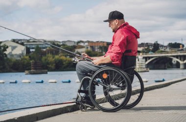 Tekerlekli sandalyede balıkçı teknesinde fiziksel engelli biri..