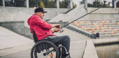 Tekerlekli sandalyede balıkçı teknesinde fiziksel engelli biri..