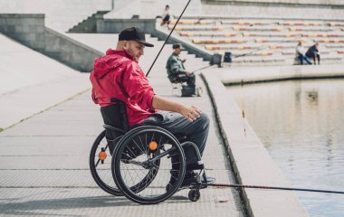 Tekerlekli sandalyede balıkçı teknesinde fiziksel engelli biri..