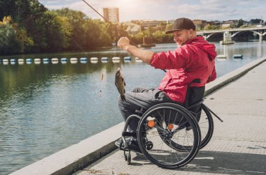 Tekerlekli sandalyede balıkçı teknesinde fiziksel engelli biri..