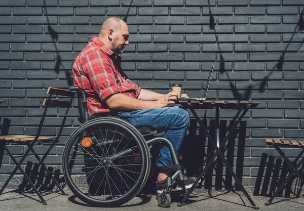 Freelancer con discapacidad física en silla de ruedas que trabaja en la cafetería de la calle — Foto de Stock