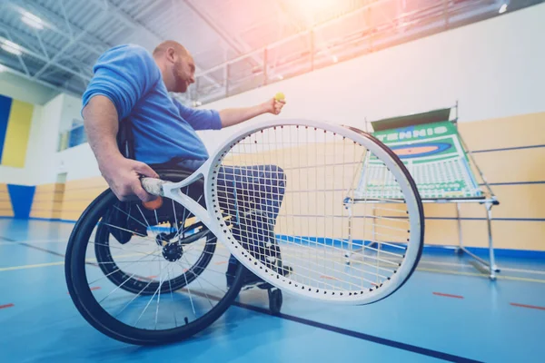 Homem adulto com deficiência física em uma cadeira de rodas jogando tênis em quadra de tênis indoor — Fotografia de Stock