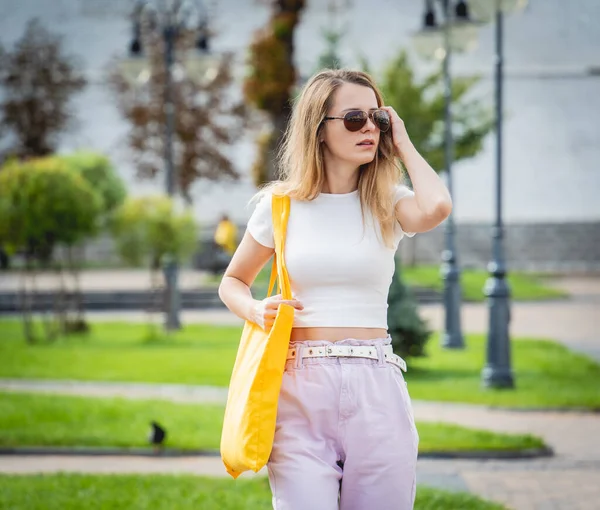 Mladá krásná žena s ložním prádlem eko taška na pozadí města. — Stock fotografie