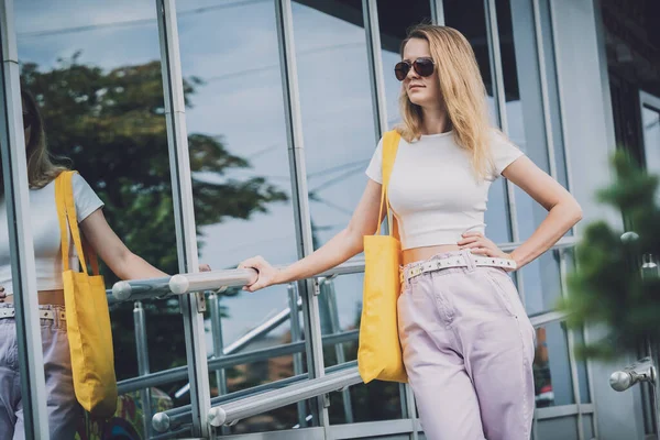 Jeune belle femme avec sac écologique en lin sur fond de ville. — Photo