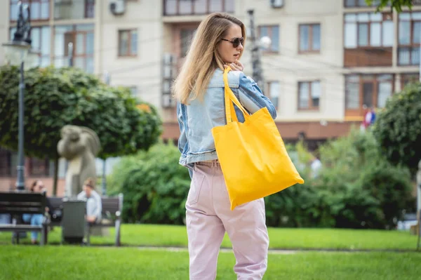 Jeune belle femme avec sac écologique en lin sur fond de ville. — Photo