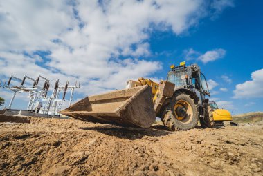 Tekerlek yükleyici kazıcı inşaat alanında çalışıyor.