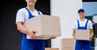 İki nakliye şirketi çalışanı bir minibüse kutu yüklüyorlar..