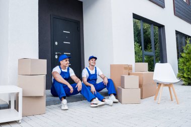 İki nakliye şirketi çalışanı merdivende otururken mola veriyor.