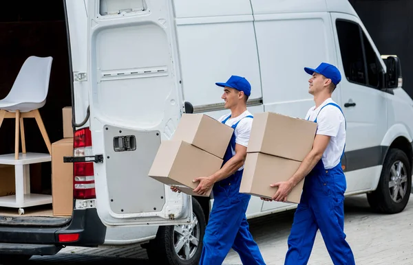 İki nakliye şirketi çalışanı bir minibüse kutu ve mobilya yüklüyorlar..