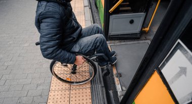 Fiziksel engelli bir kişi erişilebilir bir rampayla toplu taşımaya giriyor.