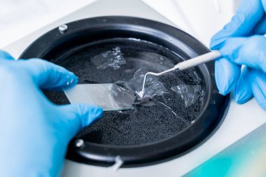 Laboratuvar asistanı bir döner mikro bölüm üzerinde çalışıyor ve mikroskop slaytları yapıyor