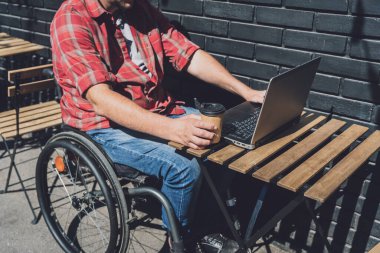 Sokak kafesinde çalışan tekerlekli sandalyede fiziksel engelli bir serbest çalışan.