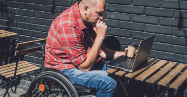 Sokak kafesinde çalışan tekerlekli sandalyede fiziksel engelli bir serbest çalışan.