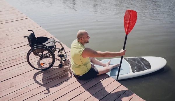 Osoba s tělesným postižením na invalidním vozíku bude jezdit na sup boardu — Stock fotografie