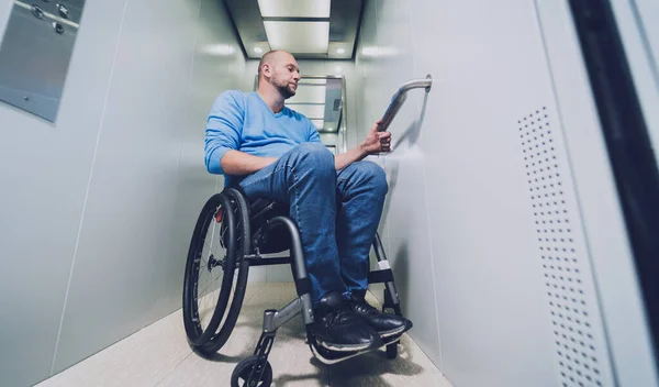 Person with a physical disability in a wheelchair using lift in building — Stock Photo, Image