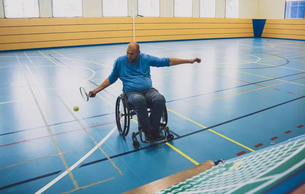 Erwachsener Mann mit körperlicher Behinderung im Rollstuhl spielt Tennis auf Tennishalle — Stockfoto