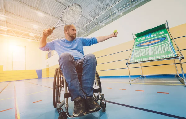 Hombre adulto con discapacidad física en silla de ruedas jugando al tenis en pista de tenis cubierta — Foto de Stock