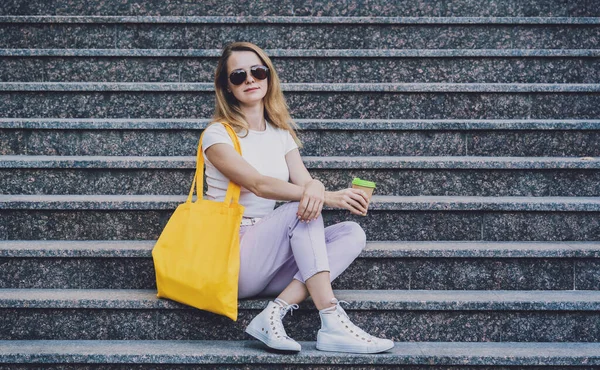 Genç ve güzel bir kadın. Arka planda keten bir çanta var..