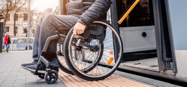 Fiziksel engelli kişiler toplu taşımadan erişilebilir bir rampayla çıkıyorlar..