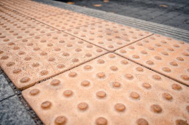 Fiziksel engelli kişiler için toplu taşıma istasyonunda sarı kabartma yazılar