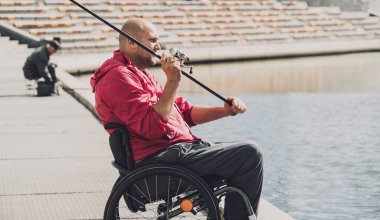 Tekerlekli sandalyede balıkçı teknesinde fiziksel engelli biri..