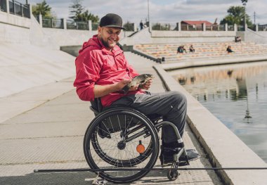 Tekerlekli sandalyede balıkçı teknesinde fiziksel engelli biri..