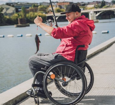 Tekerlekli sandalyede balıkçı teknesinde fiziksel engelli biri..