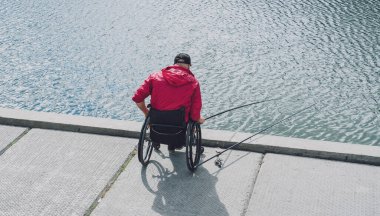 Tekerlekli sandalyede balıkçı teknesinde fiziksel engelli biri..