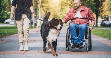 Köpeğiyle birlikte tekerlekli sandalyede fiziksel engelli mutlu bir genç adam..