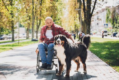 Köpeğiyle birlikte tekerlekli sandalyede fiziksel engelli mutlu bir genç adam..