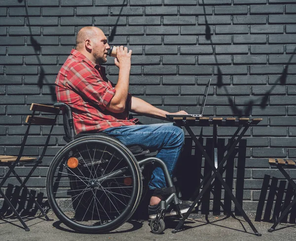 Freelancer con discapacidad física en silla de ruedas que trabaja en la cafetería de la calle — Foto de Stock